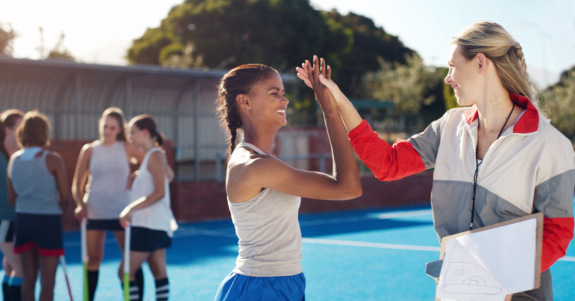 A coach and player sharing a high five at a floor hockey court.