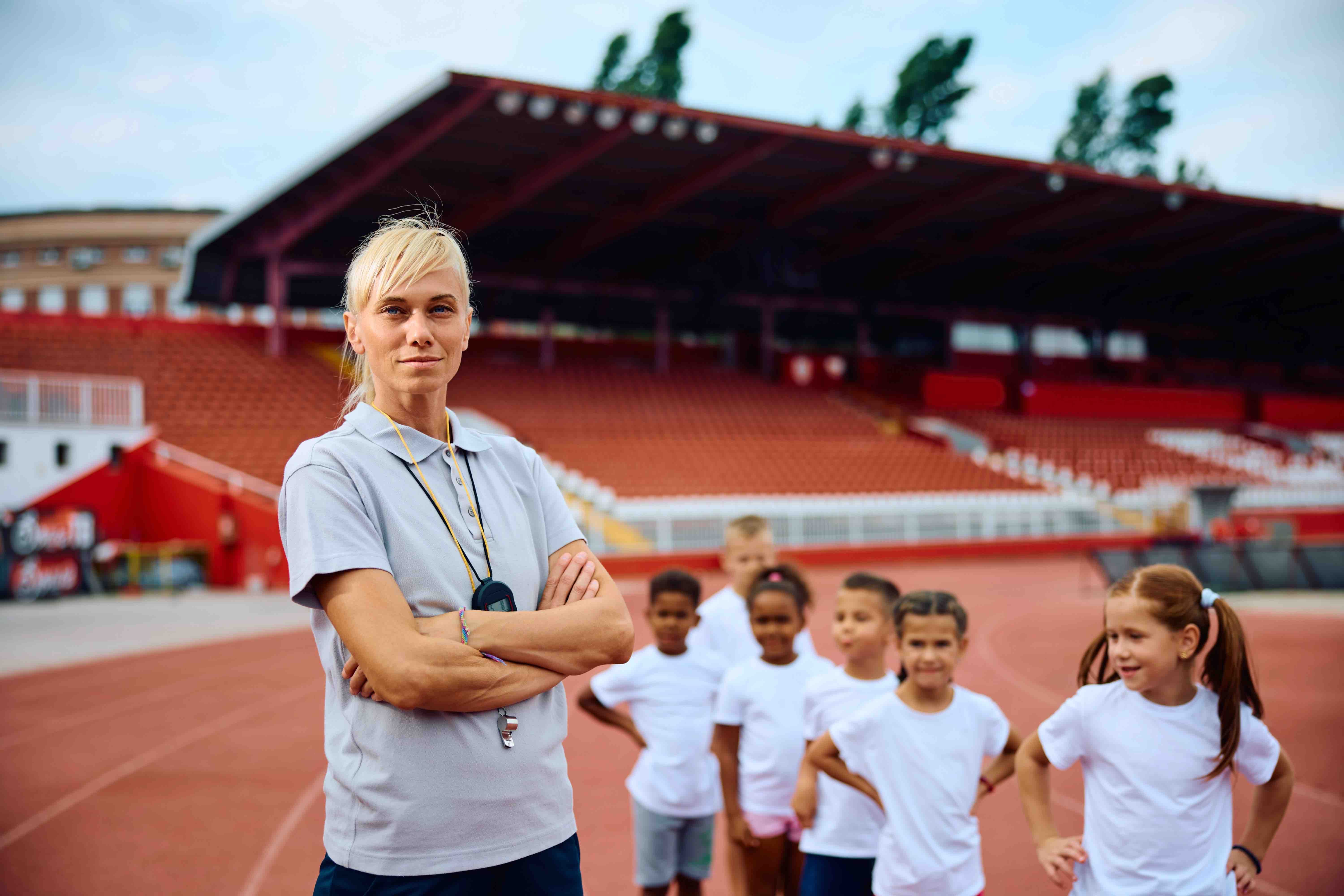 confident-coach-with-group-of-kids-at-athletic-